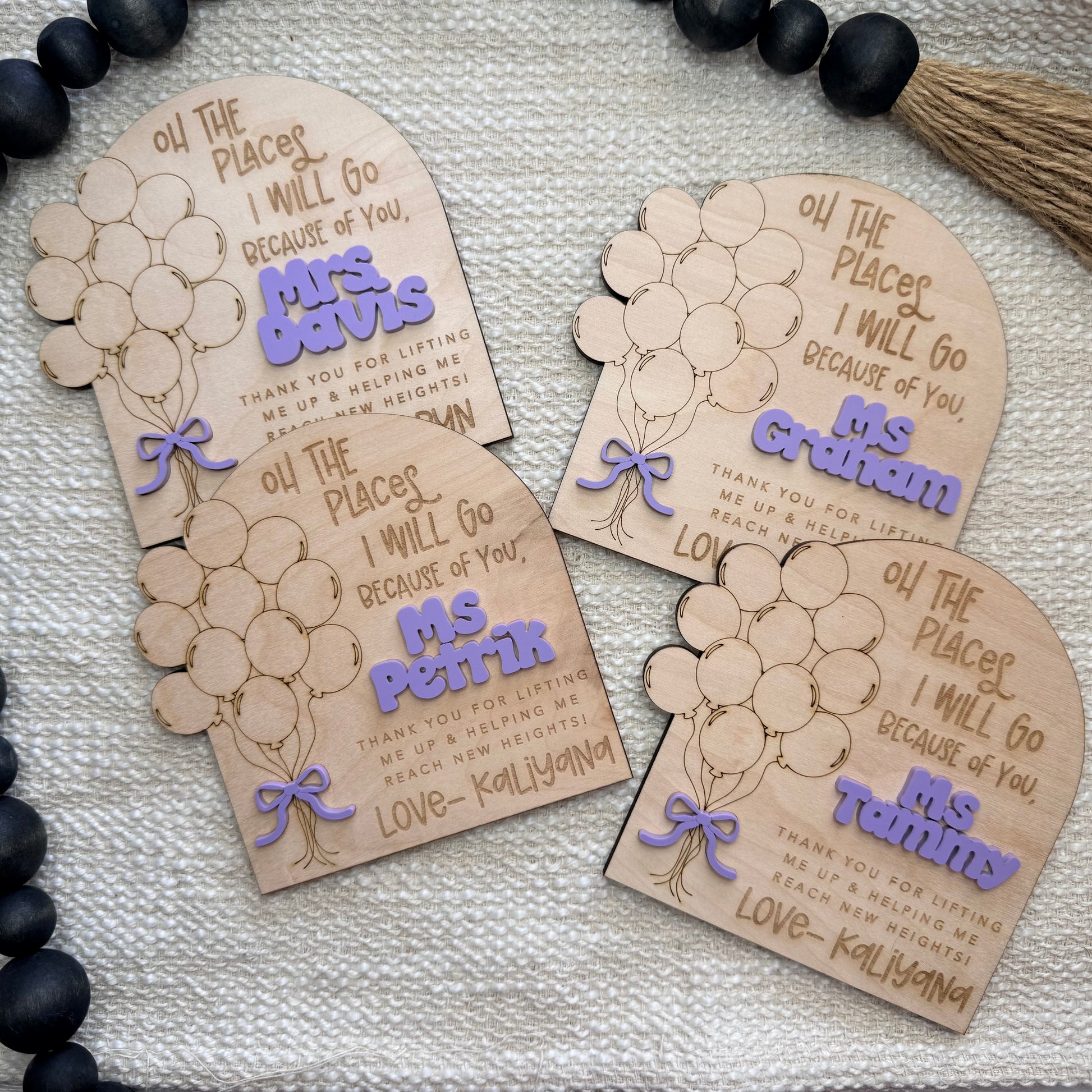 Personalized wooden name tags with balloon designs on a textured surface.